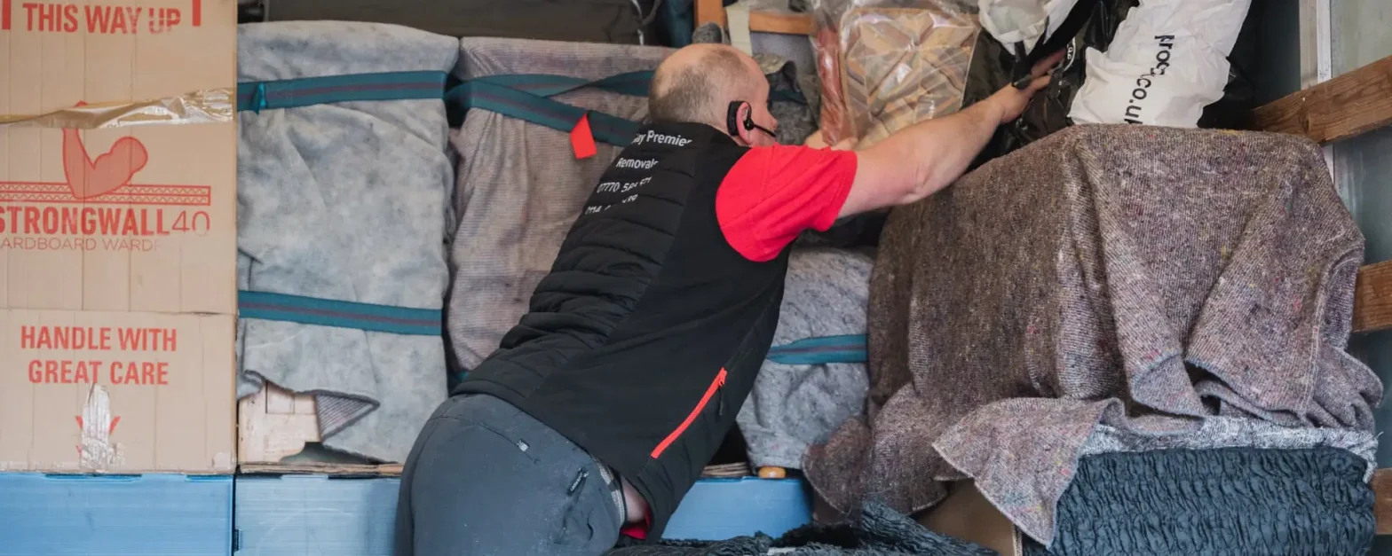 Bradway Premier Removals crew member loading blanket-wrapped furniture and boxes into the van