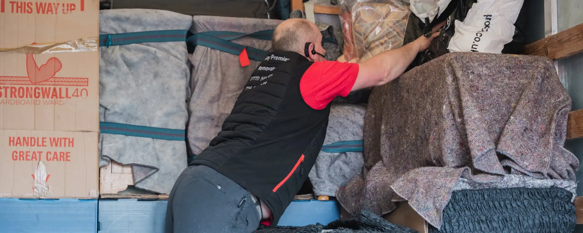 Bradway Premier Removals crew member loading blanket-wrapped furniture and boxes into the van