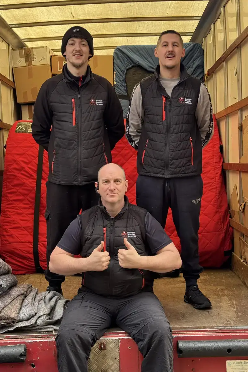 Three Bradway Premier Removals crew members giving a thumbs up in the back of a removals van