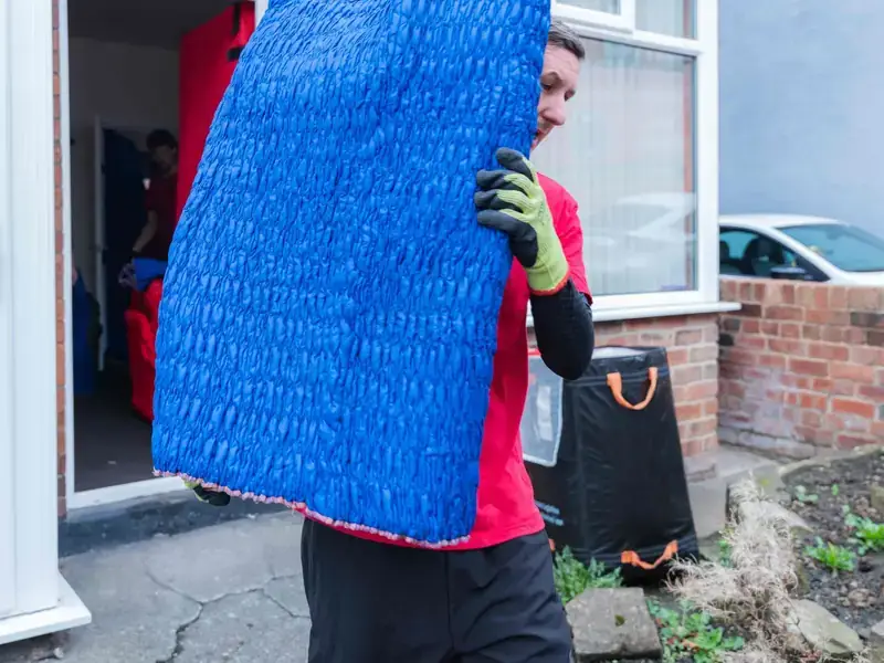 Bradway Premier Removals crew member carrying a blue wrapped item out of a house for a man and van move