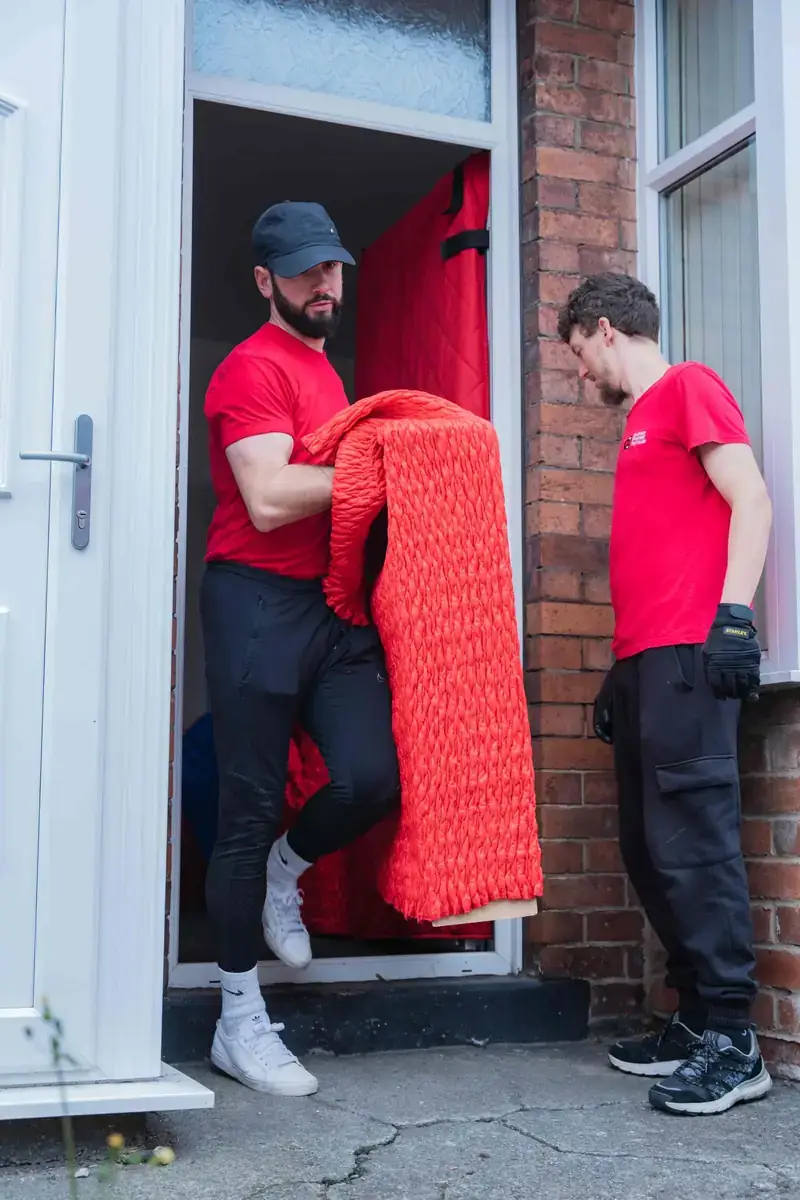 Bradway Premier Removals crew carrying protected furniture out through the front door of a Sheffield terraced house