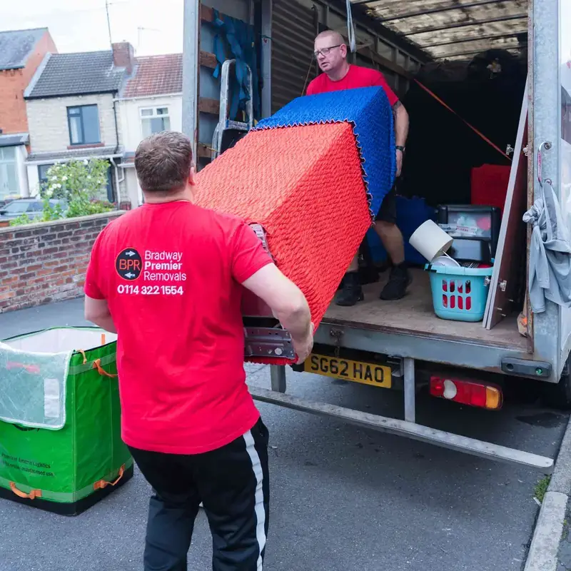 Bradway Premier Removals crew loading red and blue wrapped furniture into the removals van